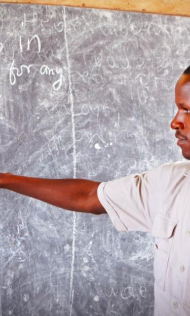 The image features a teacher standing at a blackboard.