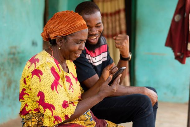 African woman and son in front of house with mobile phone