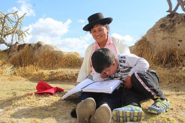 Woman and boy read a book outside in a rural setting