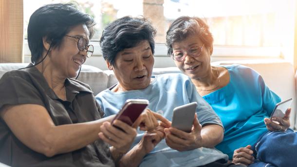 Three elderly women from Asia looking at smart phones
